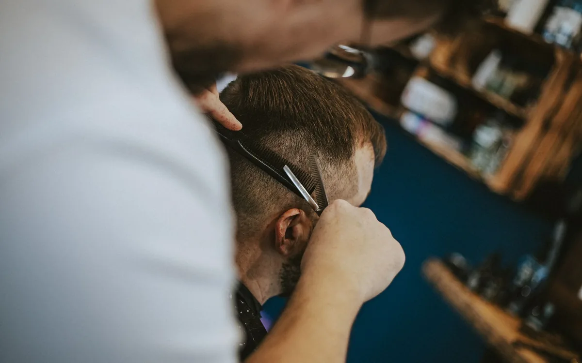 Ein Barbier schneidet einem Kunden die Haare im Salon