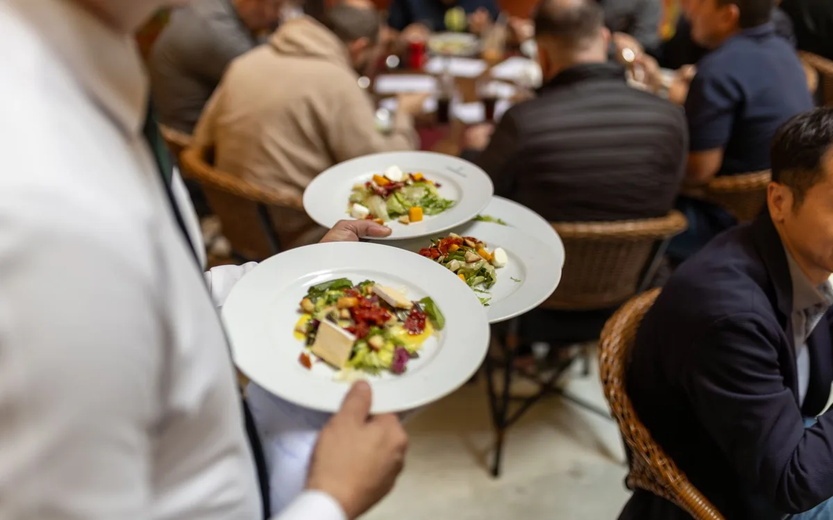 Eine Bedienung bringt Gerichte an einen Tisch in einem vollen Restaurant