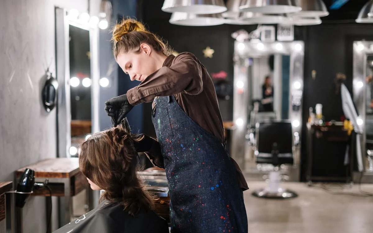 Eine Friseurin bedient eine Kundin auf dem Salonstuhl