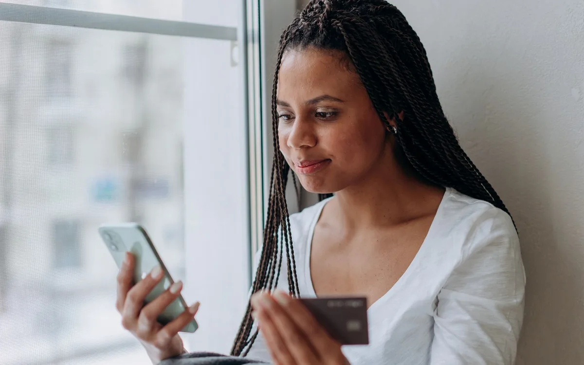 Pessoa sorrindo enquanto confere um pagamento pelo celular