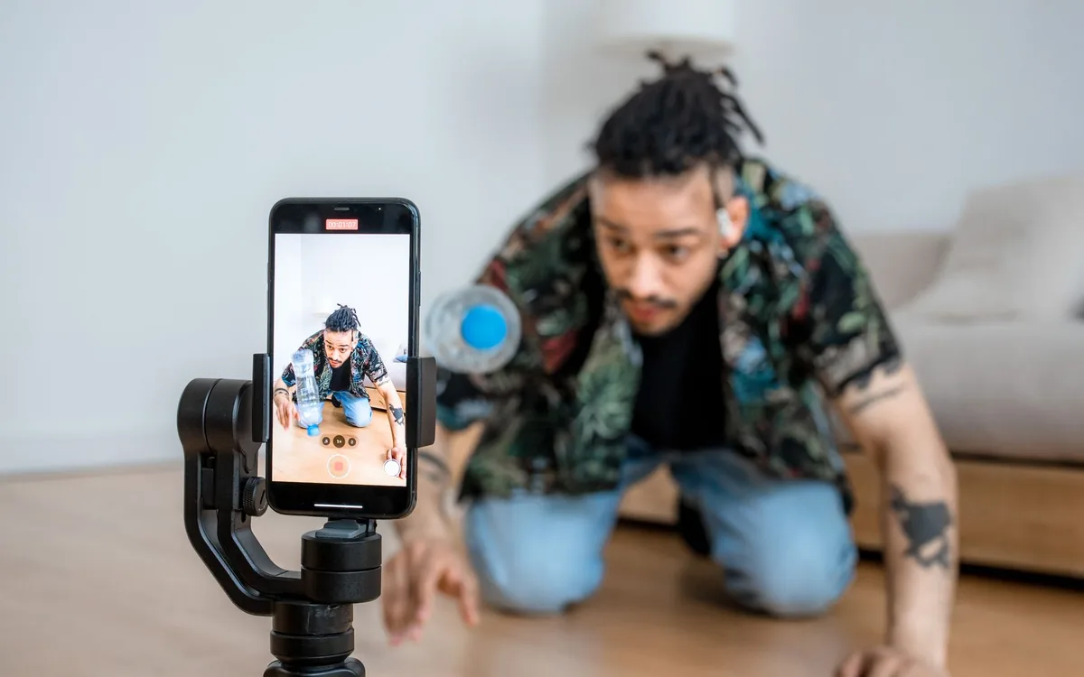 Jovem gravando vídeo com celular em estabilizador na rua
